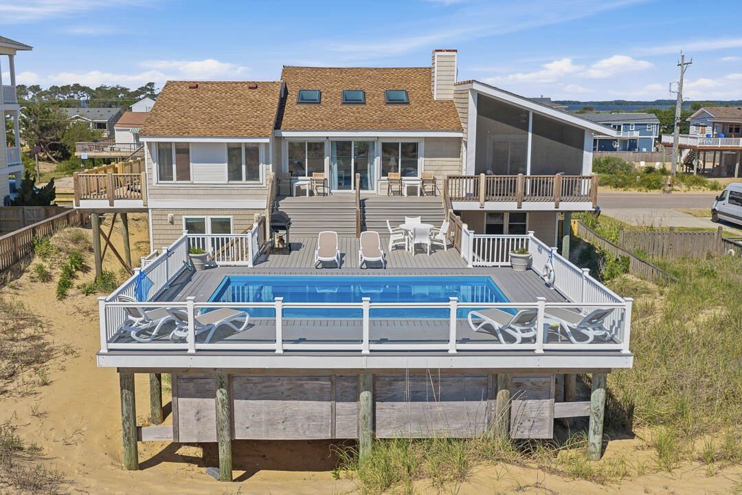 A beachfront house with a pool, deck, and multiple levels.