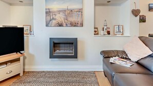 Ein Wohnzimmer mit Kamin, Fernseher und einer Couch.