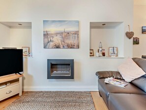 Una sala de estar con chimenea, televisor y sofá.