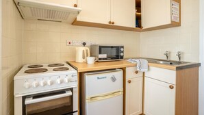 Une petite cuisine équipée avec une cuisinière, un four à micro-ondes, un réfrigérateur et un évier.