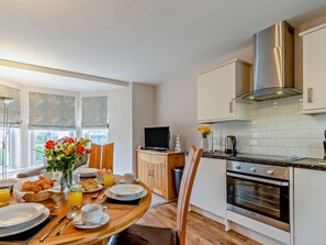 A modern kitchen with a dining area, a TV, and a large window. - 2 Bed in Tenby (oc-fb229) (Tenby)