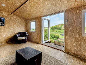 Ein Zimmer mit einer großen Schiebeglasdoor, einem Ledersessel und einem Holztisch.