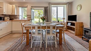 Een moderne keuken met witte kasten, een eettafel met stoelen, een televisie en een open haard.
