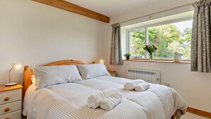 Een slaapkamer met een bed, nachtlampjes, een raam met gordijnen en een radiator.