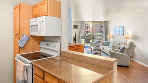 Una cocina compacta con microondas, estufa y armarios de madera.