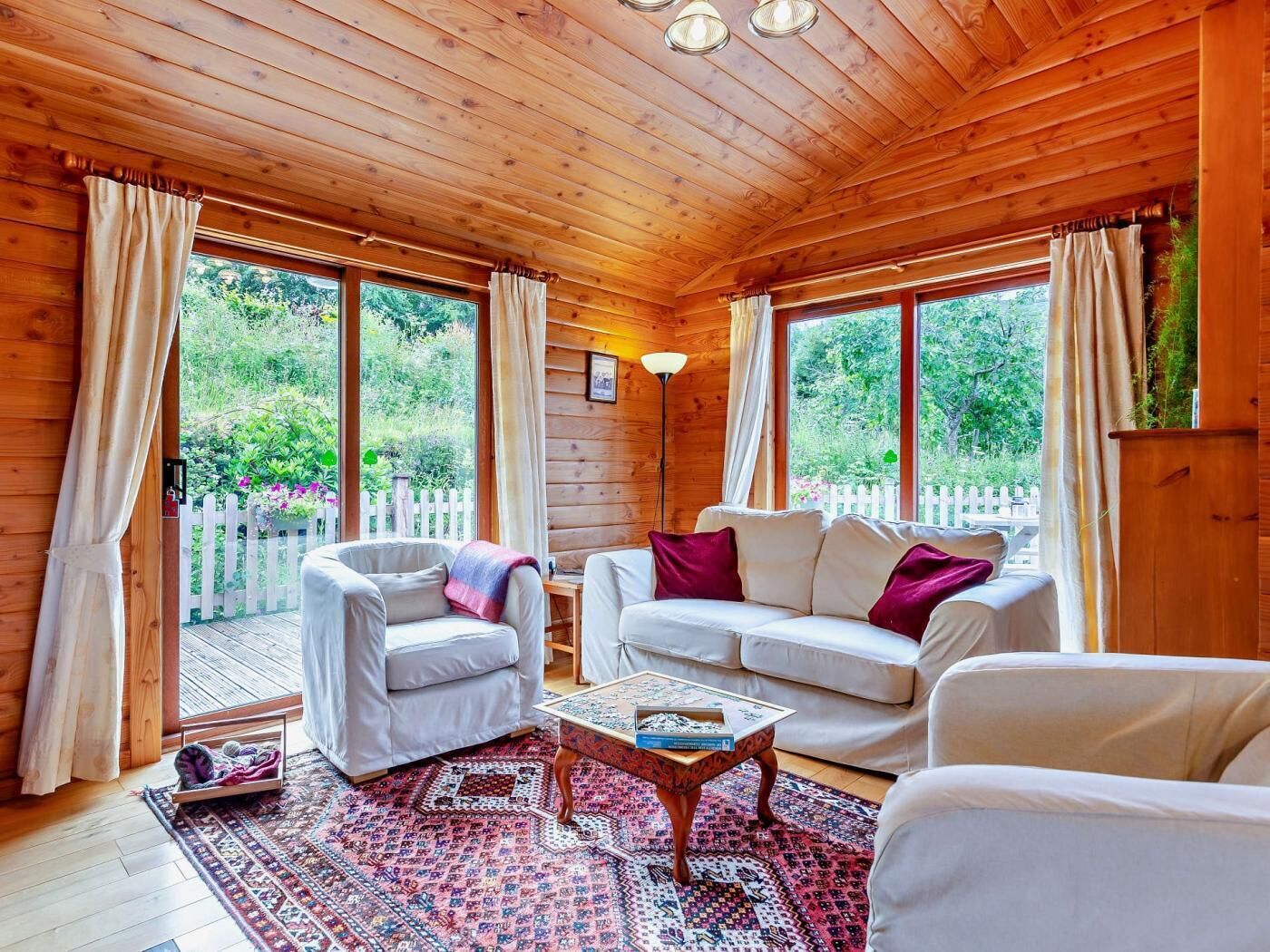 L'intérieur d'un chalet en bois, avec un canapé, un fauteuil et une table basse.