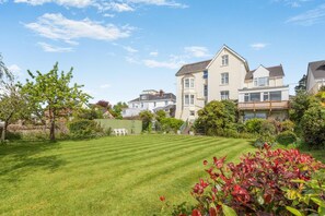 A residential area with a well-maintained lawn, a large two-story house, and a wooden fence. - 6 Bed in Bideford (oc-beaho) (Bideford)