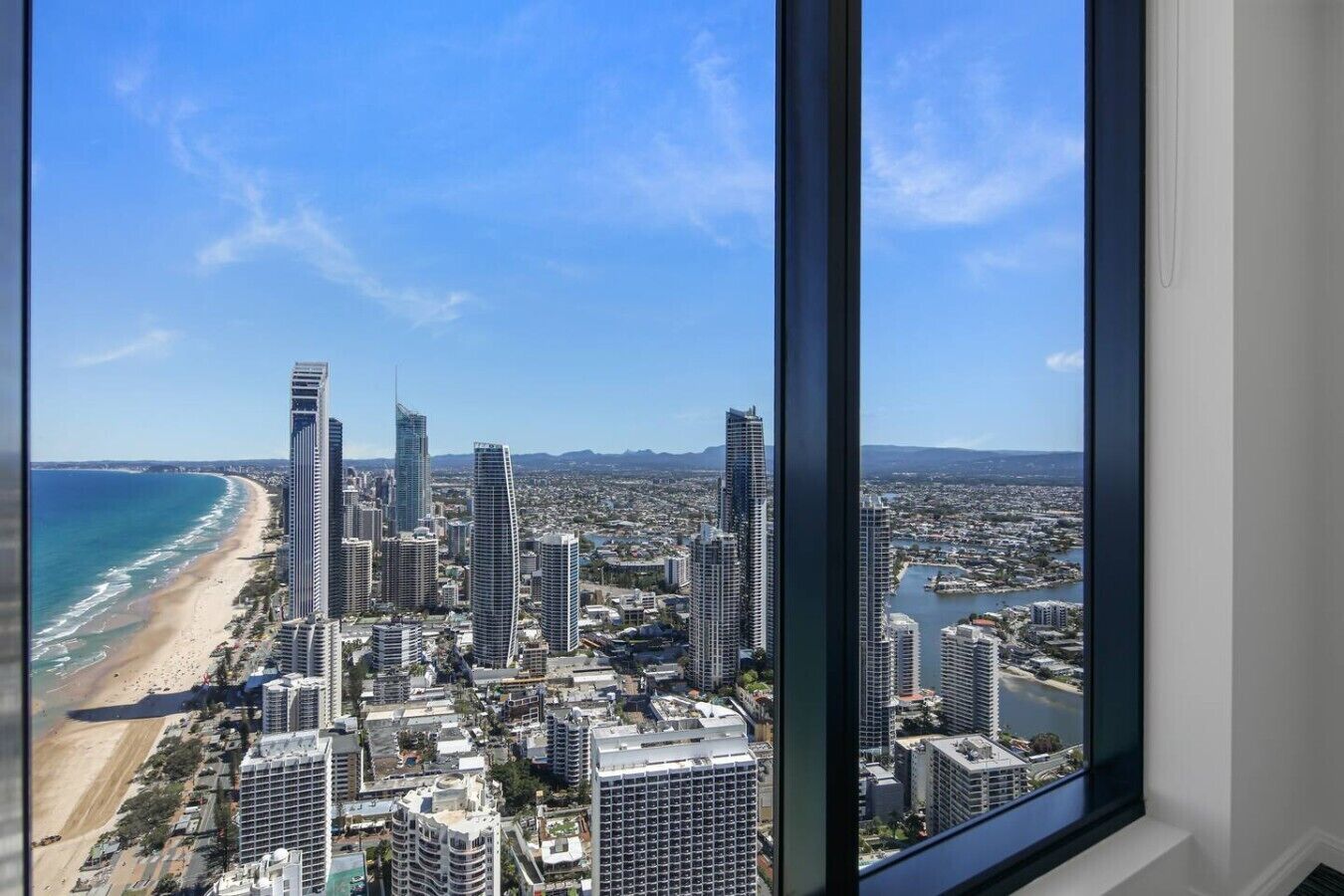 A high-rise building with a view of a beach and cityscape.