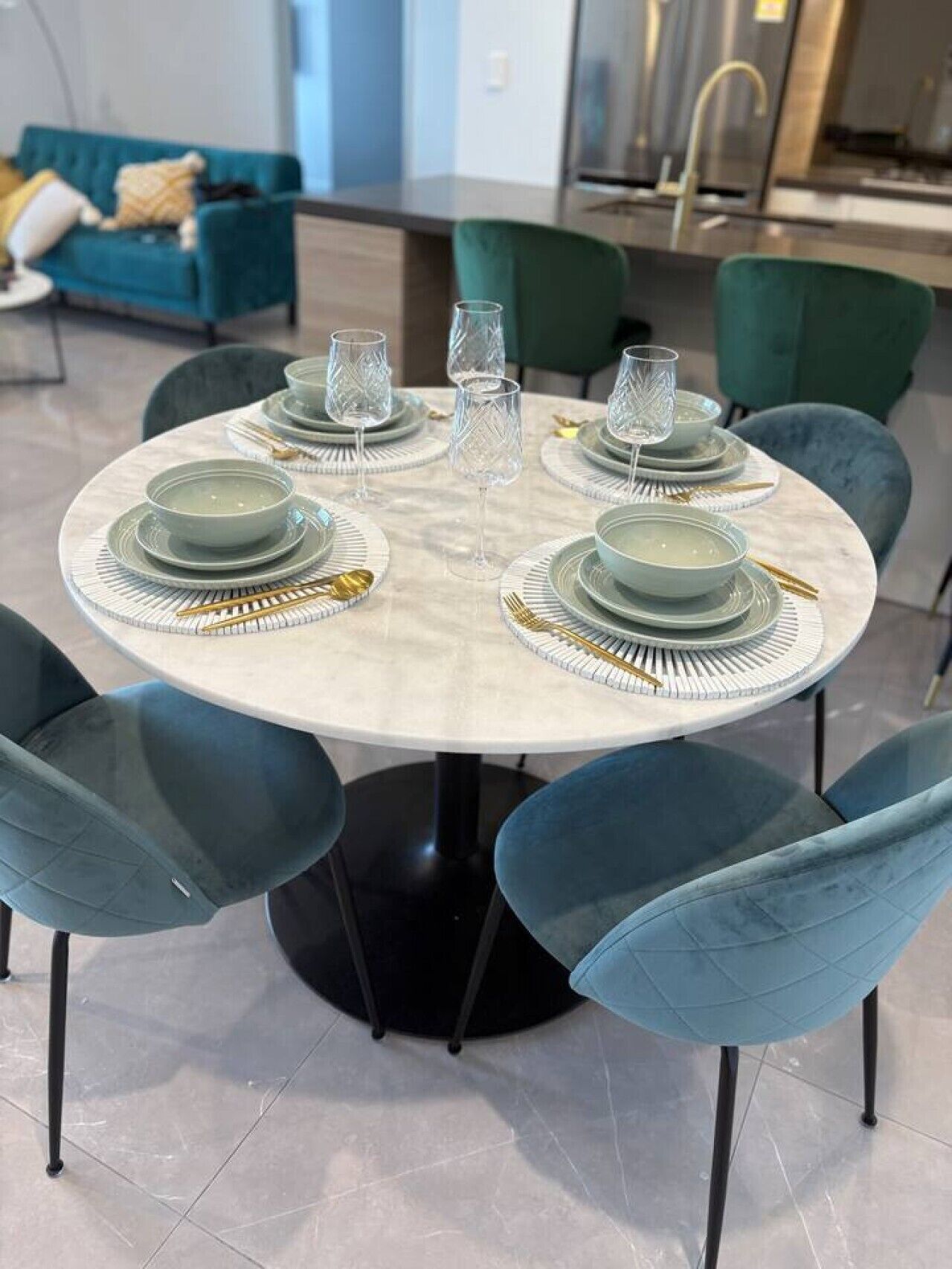 A dining table set with plates, glasses, and cutlery, surrounded by chairs.