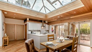 A modern kitchen with wooden cabinets, a dining area with a table and chairs, and a large skylight. - 1 Bed in Alnwick (oc-94771) (Alnwick)