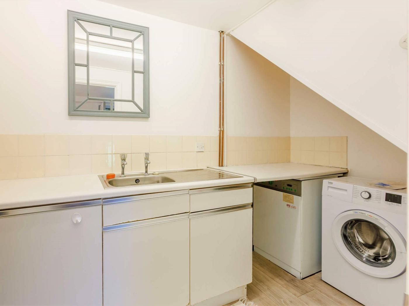 A compact kitchen with a sink, dishwasher, and washing machine.