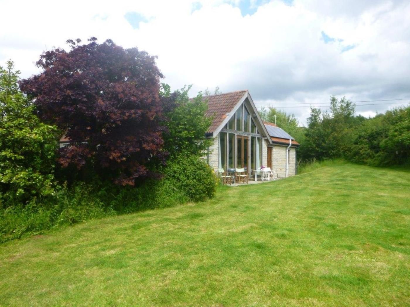 A house with a sloped roof, a visible chimney, and a lawn in front.