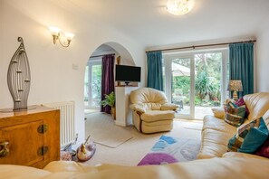 A living room with a sofa, armchair, and a flat-screen TV. There is a wooden cabinet and a decorative metal sculpture. - 1 Bed in Ringwood (oc-50147) (Ashley Heath)