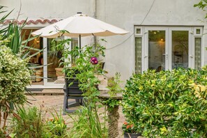 A patio area with a table and chairs, a white umbrella, and potted plants. - 1 Bed in Ringwood (oc-50147) (Ashley Heath)