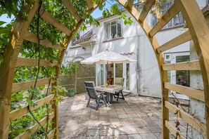 A patio with a table and chairs, a wooden pergola, and a white building with windows. - 1 Bed in Ringwood (oc-50147) (Ashley Heath)