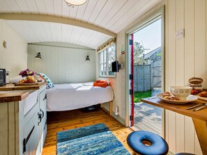 A compact room with a bed, a small kitchenette, a window, and a door leading to an outdoor area. - 1 Bed in Fowey (oc-95015) (Golant)