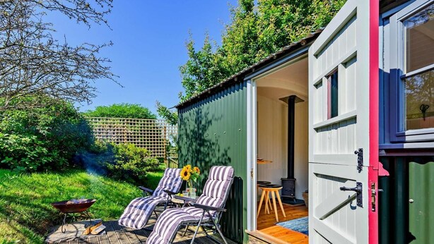 A wooden deck with striped chairs and a barbecue grill. - 1 Bed in Fowey (oc-95015) (Golant)