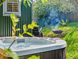 A hot tub in a backyard with a grill and a chair. - 1 Bed in Fowey (oc-95015) (Golant)