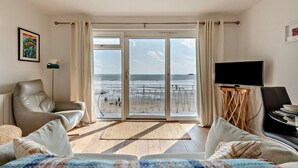 Habitación de hotel con vista a la playa, un televisor y un sofá.