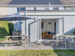 A modern house with a patio area featuring a wooden table, chairs, and an umbrella. - 3 Bed in Saundersfoot (oc-83465) (Saundersfoot)