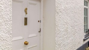 A white textured door with a brass knocker and a small window above it. - 5 Bed in Tenby (oc-83907) (Tenby)