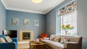 A living room with a fireplace, two sofas, a coffee table, and a TV. - 5 Bed in Tenby (oc-83907) (Tenby)