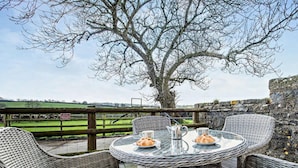 An outdoor seating area with wicker chairs and a table, a stone wall, and a view of a field. - 2 Bed in Narberth (oc-72864) (Whitland)