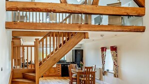 Een ruime loft met een houten trap, een keuken en een eethoek.
