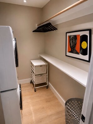 A compact kitchen with a white refrigerator, a small cart, and a framed artwork on the wall. - Modern Luxe 2BR + Office Bordering Highland Park (Dallas)