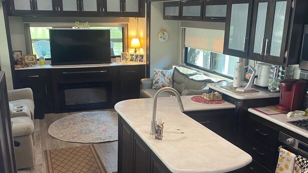 Una cocina compacta con una isla central, televisión integrada y un área de comedor con sofá.
