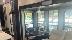 Una cocina con refrigerador, una mesa de comedor con sillas, un sofá y una ventana con vista al exterior.