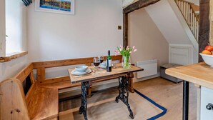 Ein Essbereich mit einer Holzbank, einem Tisch und einer Blumenvase.