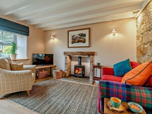 A cozy living room with a fireplace, a television, a sofa, and a table with a bowl of snacks. - 1 Bed in Ripon (oc-95009) (Grewelthorpe)