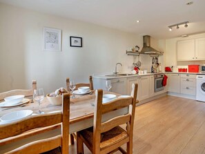 A modern kitchen with white cabinets, a wooden dining table with chairs, and a washing machine.