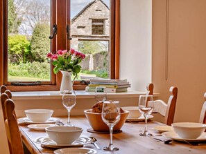 Une table à manger dressée avec des bols blancs, des verres à vin et un vase rempli de fleurs.