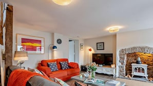 Una sala de estar con un sofá, una mesa de centro, un televisor y una chimenea de piedra.