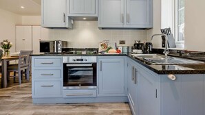 Uma cozinha moderna com armários azul claro, forno embutido e micro-ondas.