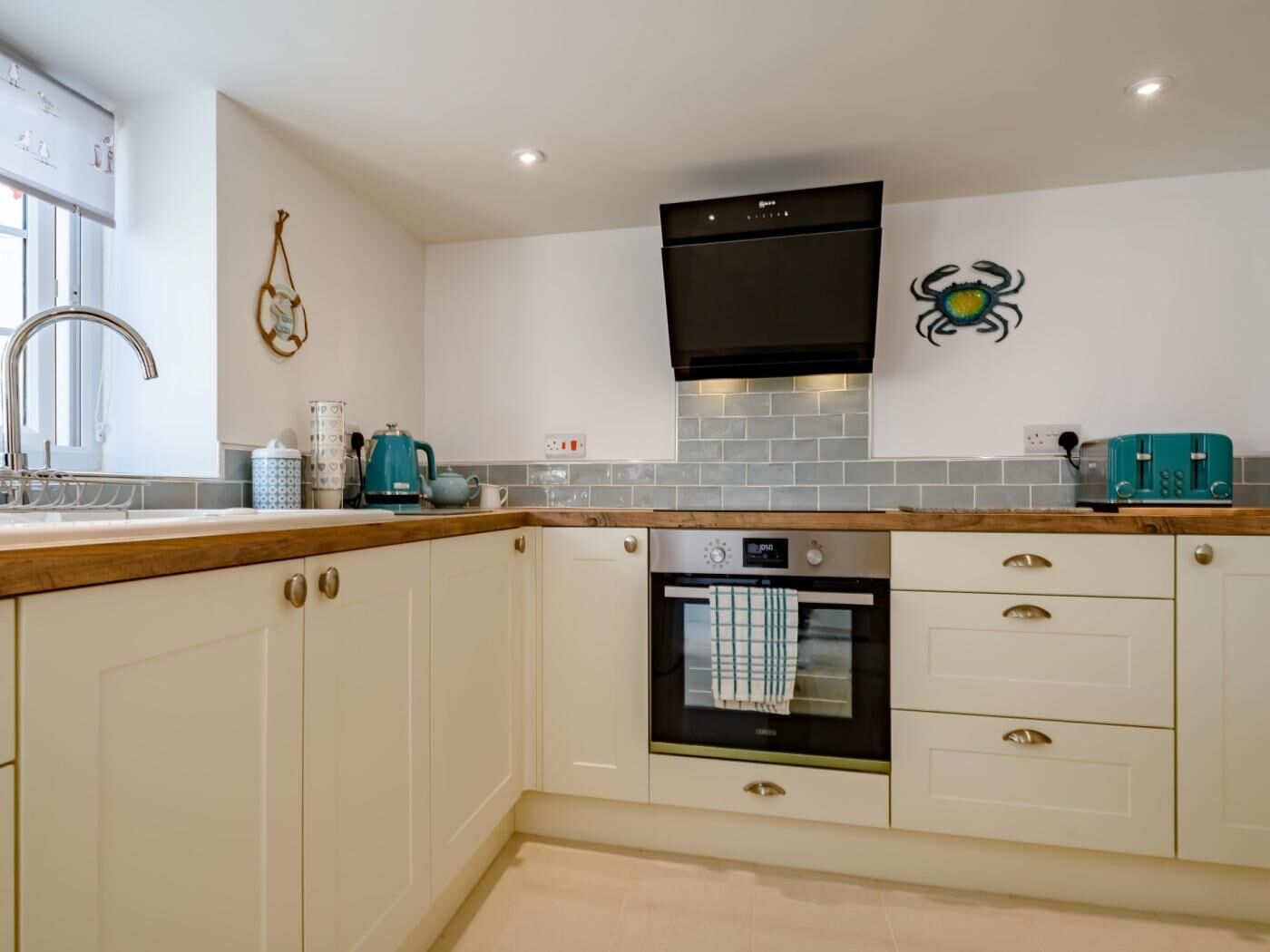 A modern kitchen with white cabinetry, a built-in oven, and a stainless steel range hood.