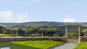 A rural landscape with rolling hills, a stone pathway, and a metal gate. - 3 Bed in Ratlinghope (oc-79238) (Ratlinghope)