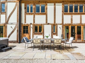 A courtyard with a stone patio, a round table with chairs, and a grill. - 4 Bed in Wrexham (oc-87675) (Pont-y-blew)