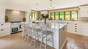 A spacious kitchen with a central island, bar stools, a built-in oven, and large windows. - 4 Bed in Wrexham (oc-87675) (Pont-y-blew)