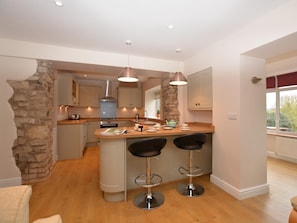 A modern kitchen with a central island, bar stools, and pendant lighting. - 3 Bed in Shrewsbury (oc-40595) (Pontesbury)