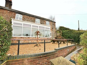 A stone building with large windows, a wooden deck, and a stone wall. - 3 Bed in Shrewsbury (oc-40595) (Pontesbury)