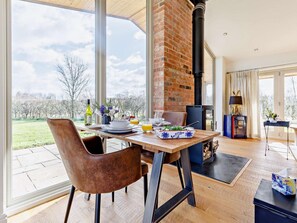 Un comedor con chimenea de ladrillo, una mesa puesta para dos personas y vistas al exterior.