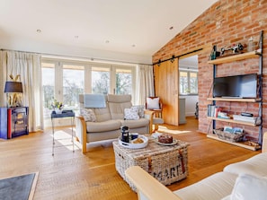 A living room with a sofa, a coffee table with a cake, a TV on a wall, and a bookshelf. - 1 Bed in Ellesmere (oc-76391) (Lyneal)