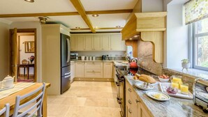 A kitchen with a wooden ceiling, a refrigerator, a stove, and a window with a view. - 6 Bed in Bala (oc-80348) (Fron-goch)