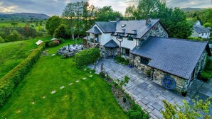A large house with a stone exterior, multiple chimneys, and a well-maintained lawn. - 6 Bed in Bala (oc-80348) (Fron-goch)