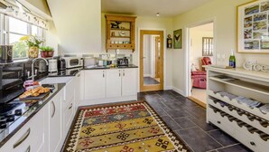 A kitchen with white cabinets, a microwave, a coffee machine, and a rug. - 1 Bed in Ruthin (oc-83640) (Llanfwrog)