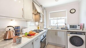 Une cuisine moderne équipée d’appareils électroménagers en acier inoxydable, d’un four encastré et d’un lave-linge.