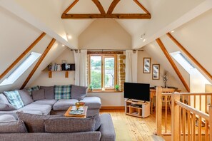 A loft-style living room with a sofa, television, and wooden beams. - 2 Bed in Bridport (oc-dc111) (Chideock)